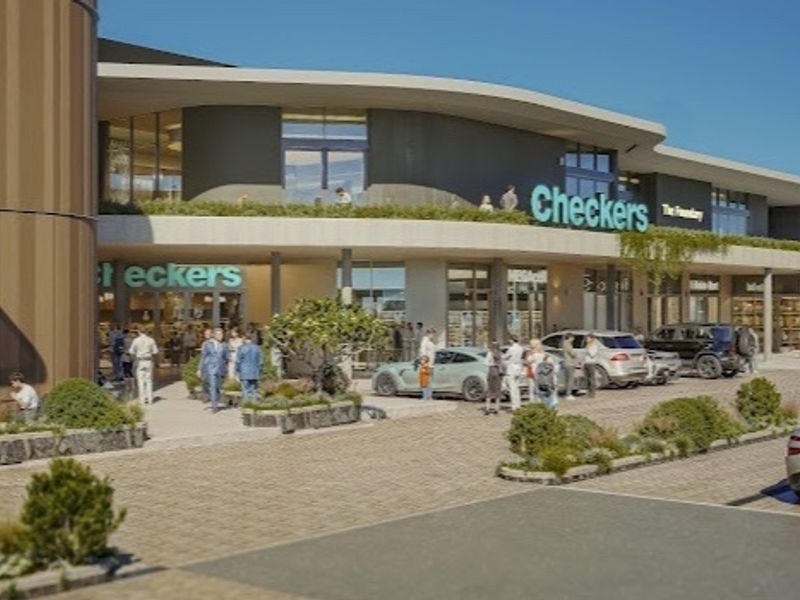 Modern commercial building exterior featuring a paved parking area, landscaped planters, and a covered walkway entrance for retail tenants.