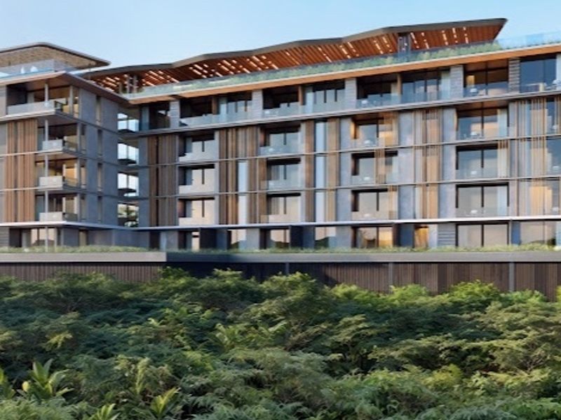 A modern multi-story apartment building featuring contemporary architectural design, glass balconies, and timber screening elements overlooking lush greenery.