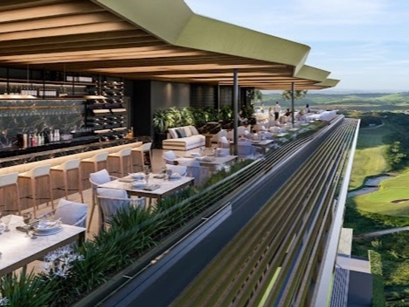 A sophisticated outdoor bar area featuring a built-in counter and integrated wine storage, set under a modern architectural roof with expansive golf course views.