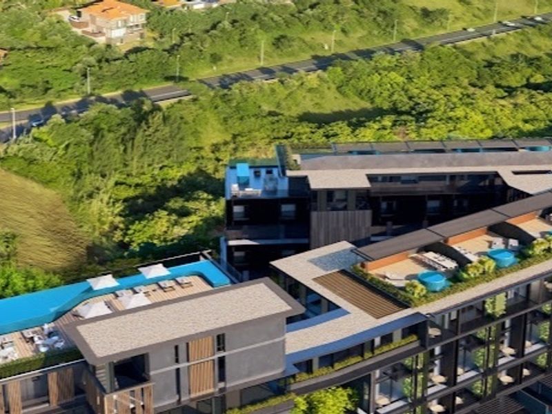 Aerial view of a modern apartment complex featuring a rooftop swimming pool, landscaped terrace areas, and contemporary architectural design.
