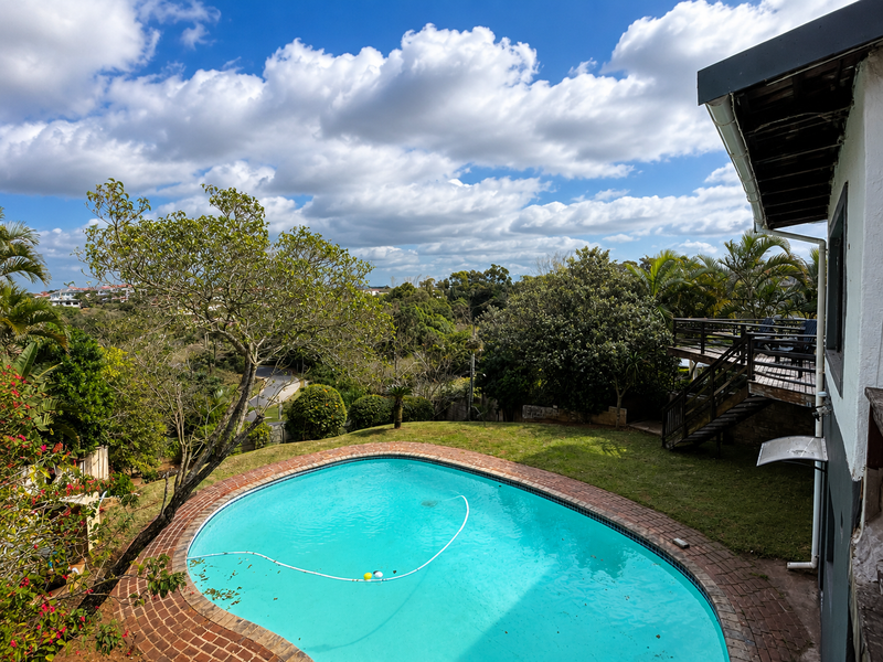Outdoor pool area featuring a swimming pool with brick coping, adjacent wooden deck, and elevated views of the surrounding landscape.
