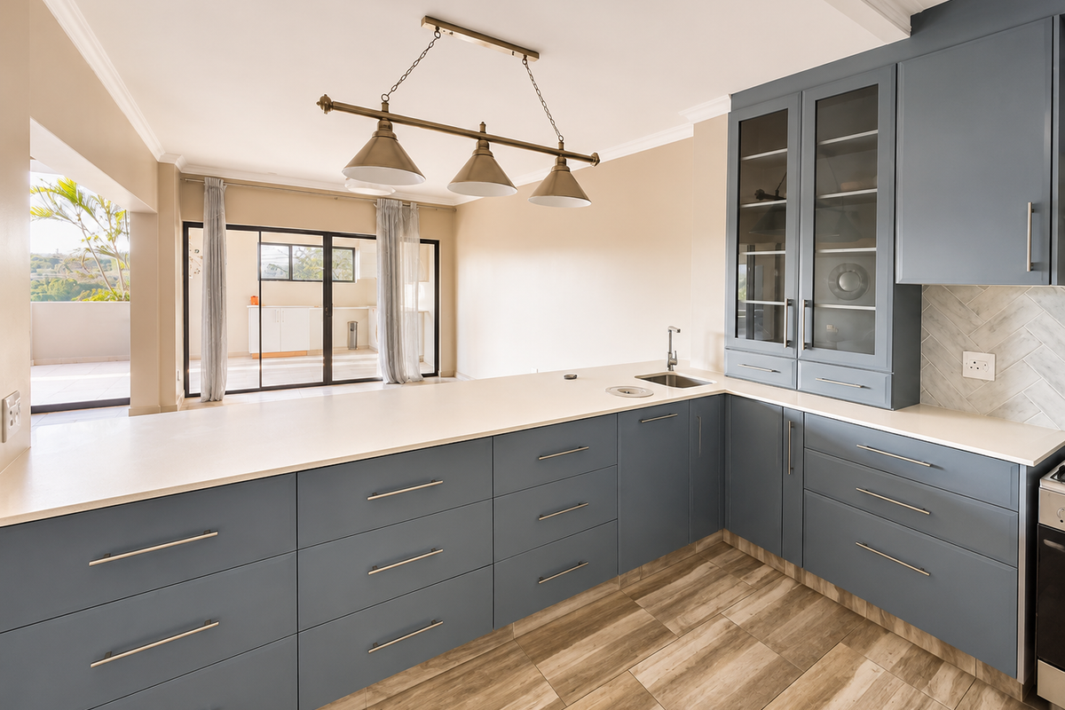 Modern kitchen featuring blue cabinetry, stone countertops, herringbone backsplash, and wood-look tile flooring, with seamless flow to an outdoor patio area.