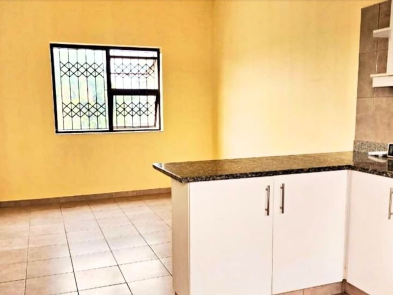 Open plan kitchen and living area featuring tiled flooring, granite countertops, and a built-in oven with extractor fan.