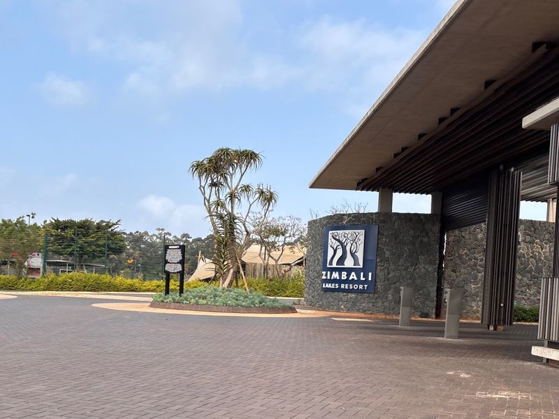The entrance to Zimbali Lakes Resort featuring a paved driveway, stone-clad signage wall, and modern architectural canopy structure.