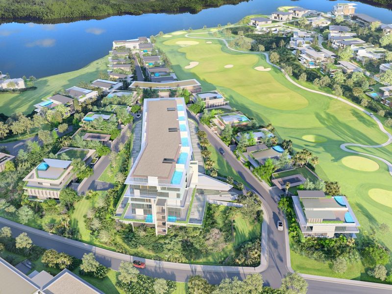 An aerial view of a residential estate featuring a golf course, waterfront access, and modern multi-story building developments.