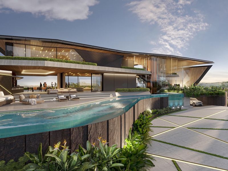 A luxury modern architectural residence featuring a striking infinity edge pool, expansive glass facades, and sophisticated stone detailing in a landscaped setting.