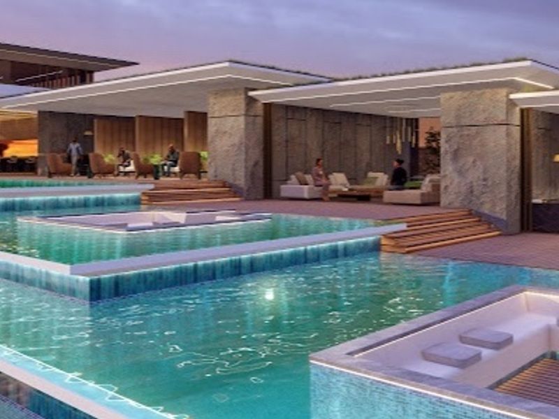 A luxurious multi-level infinity pool area featuring integrated sunken seating, stone architectural elements, and modern timber decking in a high-end penthouse setting.