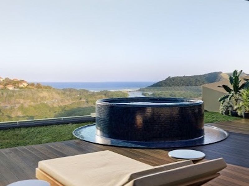 A luxury penthouse balcony featuring a built-in circular plunge pool with expansive coastal and landscape views.