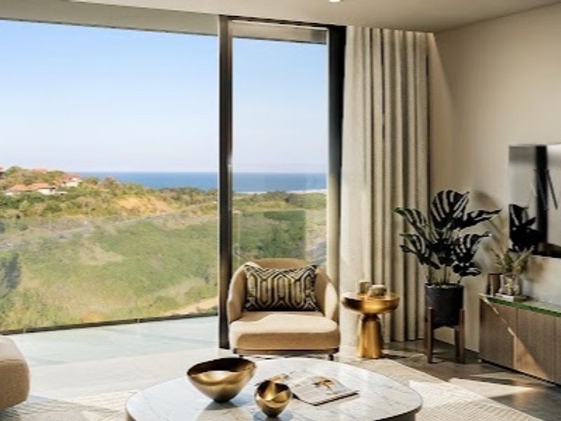 Modern living room featuring floor-to-ceiling glass doors with expansive coastal and landscape views, integrated cabinetry, and high-end finishes.