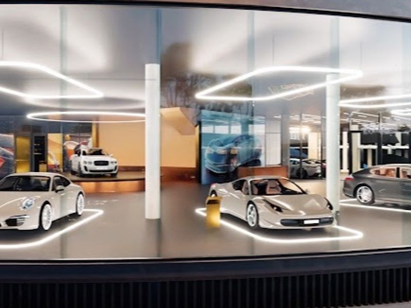 A modern, high-end luxury garage featuring a curved glass exterior, polished flooring, and integrated LED lighting, designed for premium vehicle display.