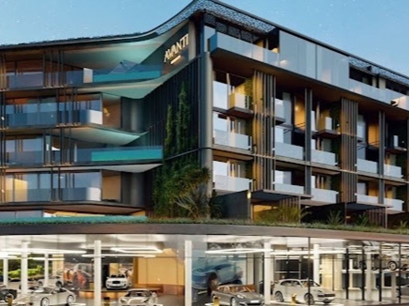 Modern multi-story penthouse building featuring contemporary architectural design, glass balconies, and a covered ground-level parking area.