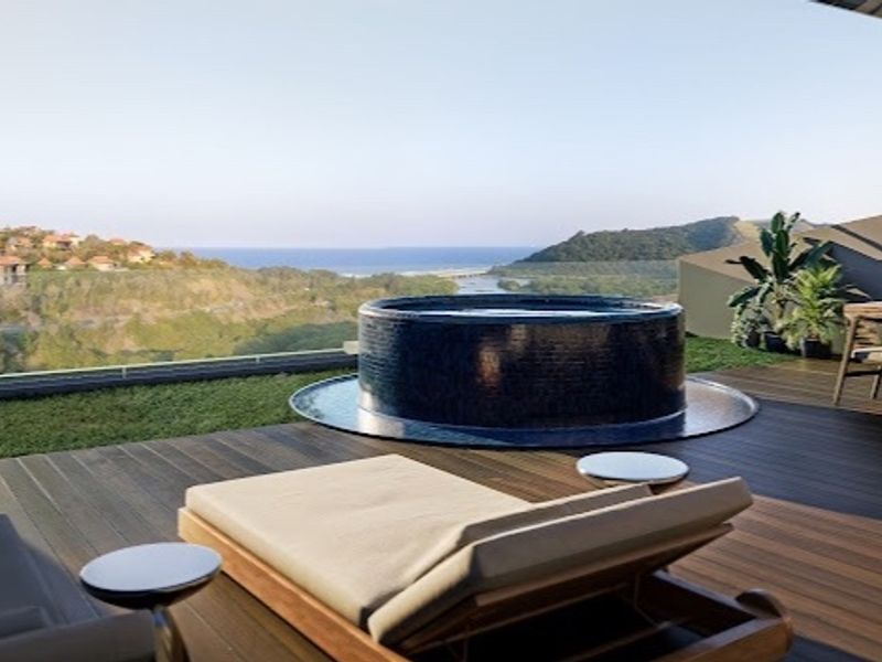 Spacious penthouse balcony featuring timber decking, a built-in circular plunge pool, and panoramic coastal views.