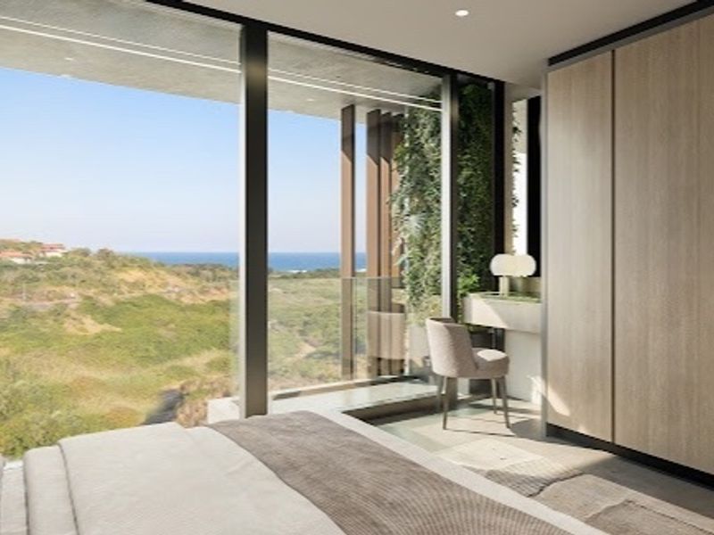 Modern bedroom featuring floor-to-ceiling windows with expansive coastal views, integrated built-in wardrobes, and high-end contemporary finishes.