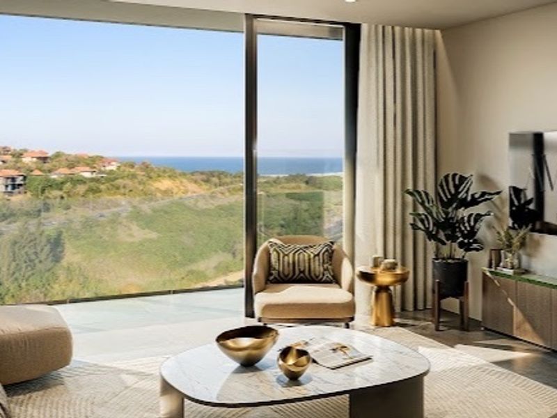 Modern living room featuring floor-to-ceiling glass doors with expansive coastal and landscape views, integrated lighting, and high-end finishes.