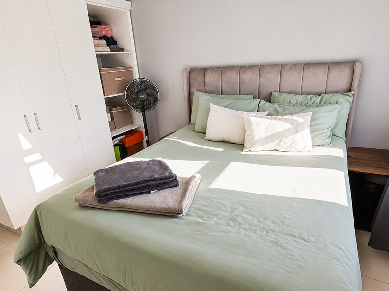 A well-maintained bedroom featuring a built-in wardrobe and neutral tiled flooring, offering a clean and functional living space.