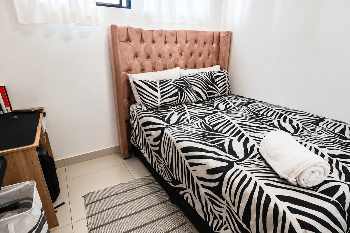 A compact bedroom featuring neutral tiled flooring and clean white walls, providing a simple and functional living space.