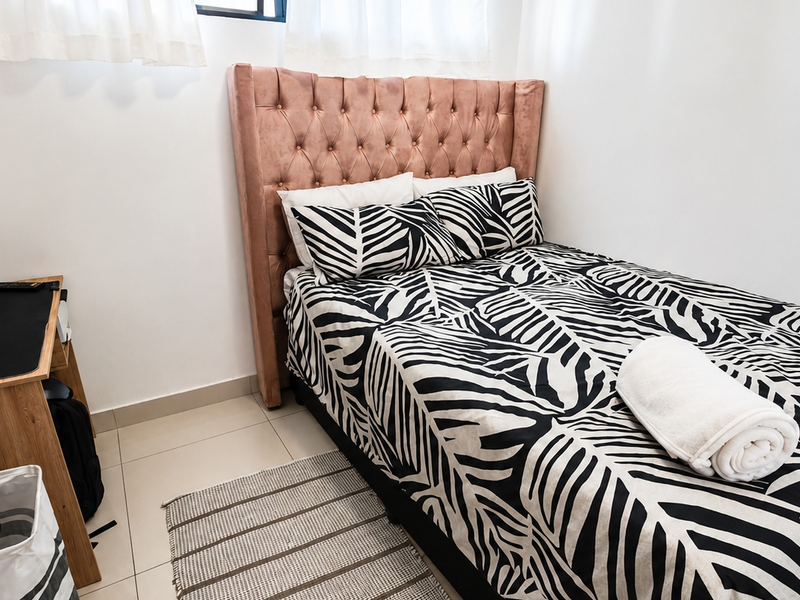 A compact bedroom featuring neutral tiled flooring and clean white walls, providing a simple and functional living space.