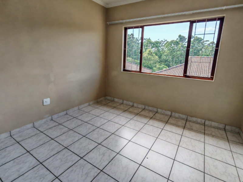 An empty bedroom featuring tiled flooring, a window with security bars, and neutral wall finishes, offering a blank canvas for personalization.