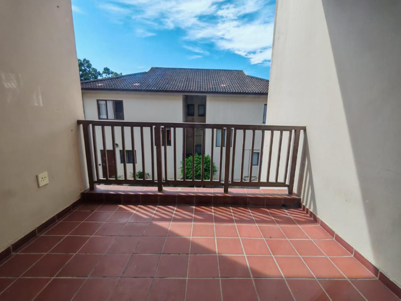 A private balcony featuring tiled flooring and a wooden balustrade, offering an open outdoor space for relaxation.