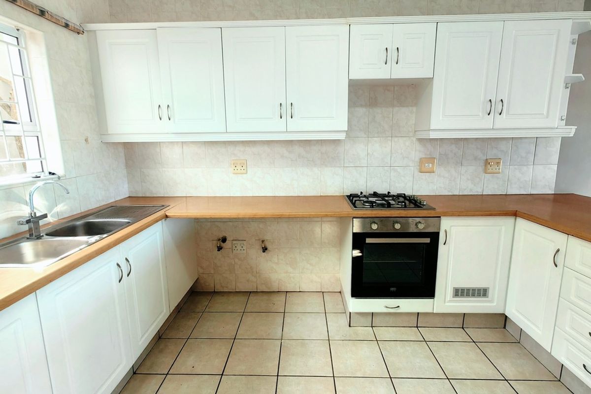 A functional kitchen featuring white cabinetry, laminate countertops, a gas hob, built-in oven, and tiled flooring with a neutral backsplash.