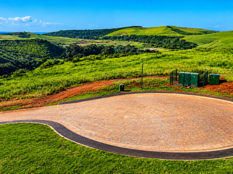An aerial view of a paved cul-de-sac turnaround area situated within a scenic, green landscape with rolling hills.
