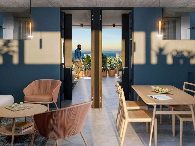 Modern open-plan living and kitchen area featuring sleek cabinetry, stone countertops, and seamless access to a private balcony with ocean views.