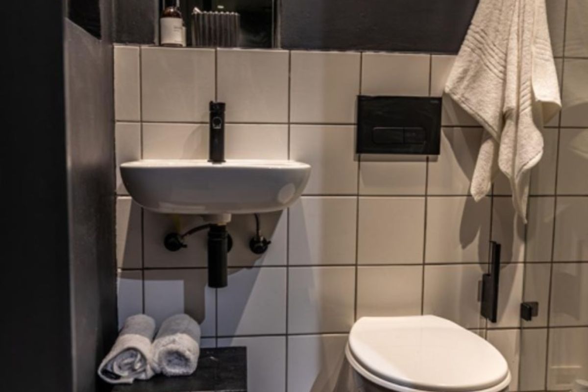 Modern bathroom featuring a wall-mounted basin, wall-hung toilet with concealed cistern, and contemporary black tapware against a tiled backdrop.