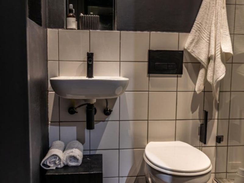 Modern bathroom featuring a wall-mounted basin, wall-hung toilet with concealed cistern, and contemporary black tapware against a tiled backdrop.