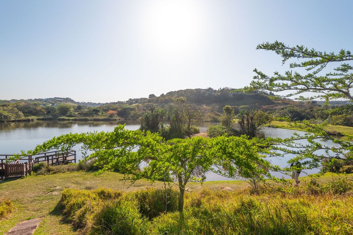 A scenic view of a tranquil lake featuring a wooden jetty and lush natural surroundings, highlighting the peaceful landscape of the property.