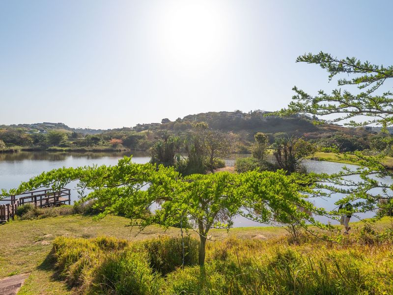 A scenic view of a tranquil lake featuring a wooden jetty and lush natural surroundings, highlighting the peaceful landscape of the property.