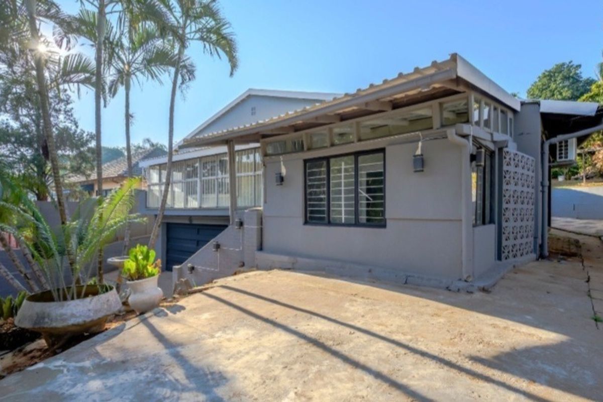 Rear exterior view of the property featuring a concrete patio area, metal roofing, and decorative breeze block detailing.