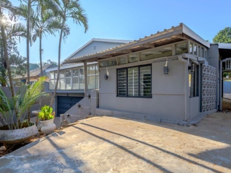 Rear exterior view of the property featuring a concrete patio area, metal roofing, and decorative breeze block detailing.