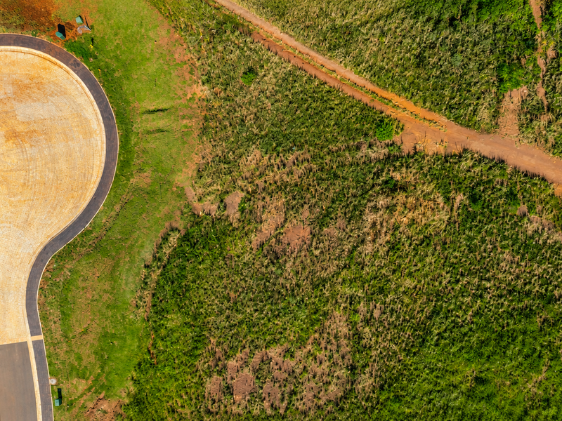 Aerial view of a paved cul-de-sac and access road surrounded by undeveloped land and vegetation.