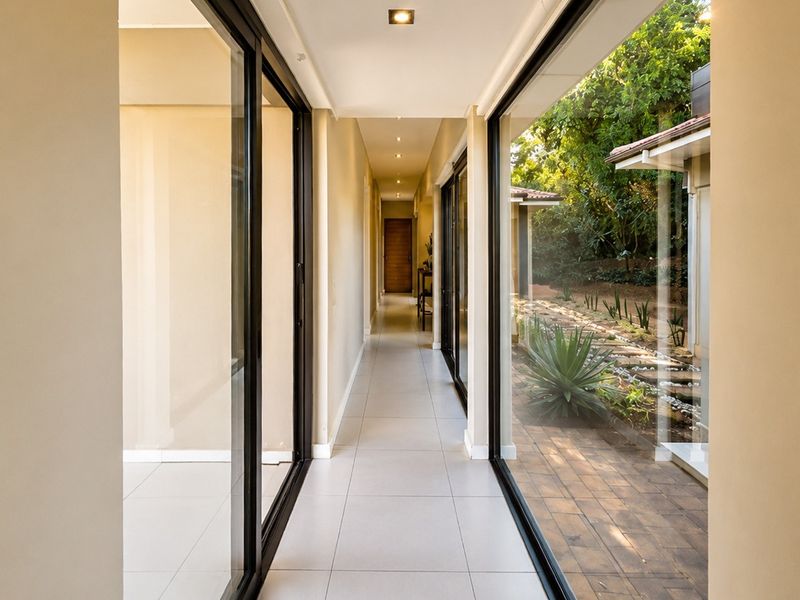 A bright, modern hallway featuring large sliding glass doors that provide views of the garden and allow for ample natural light.