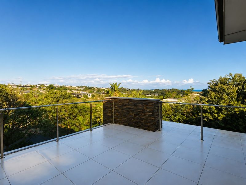 Spacious balcony featuring tiled flooring, a modern stainless steel and glass balustrade, and a stone-clad built-in counter with expansive elevated views.