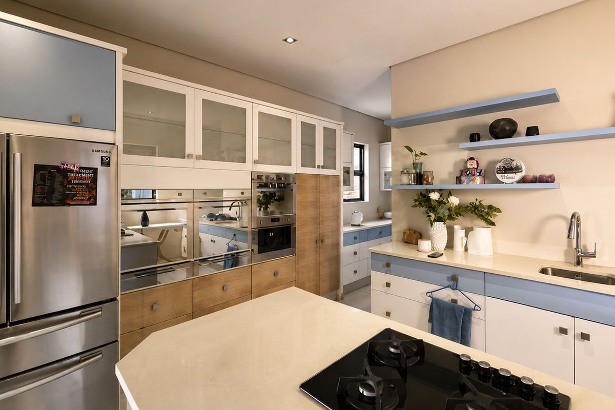 Modern kitchen featuring two-tone cabinetry, stone countertops, integrated appliances, a gas hob, and open shelving for a clean, functional design.
