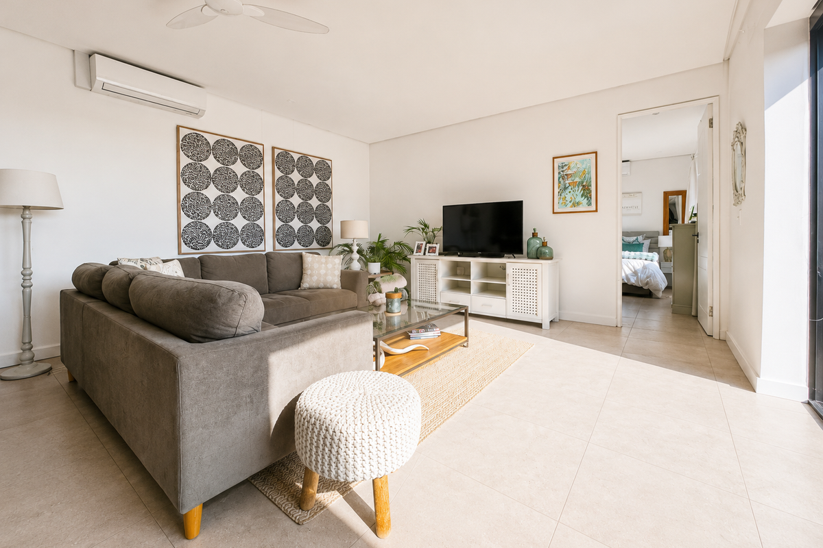 A bright and modern living room featuring tiled flooring, a ceiling fan, and a wall-mounted air conditioning unit with access to an outdoor area.