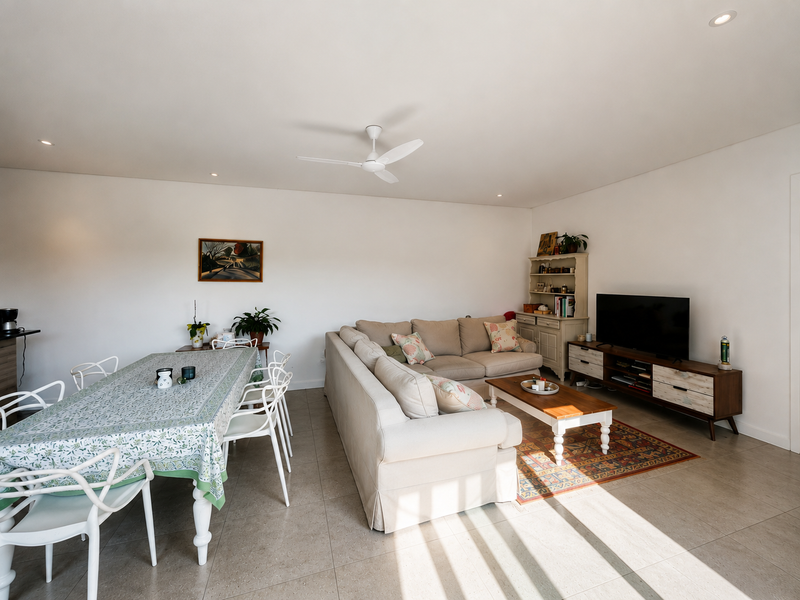 Spacious open-plan living and dining area featuring neutral tiled flooring, recessed downlighting, and a central ceiling fan.