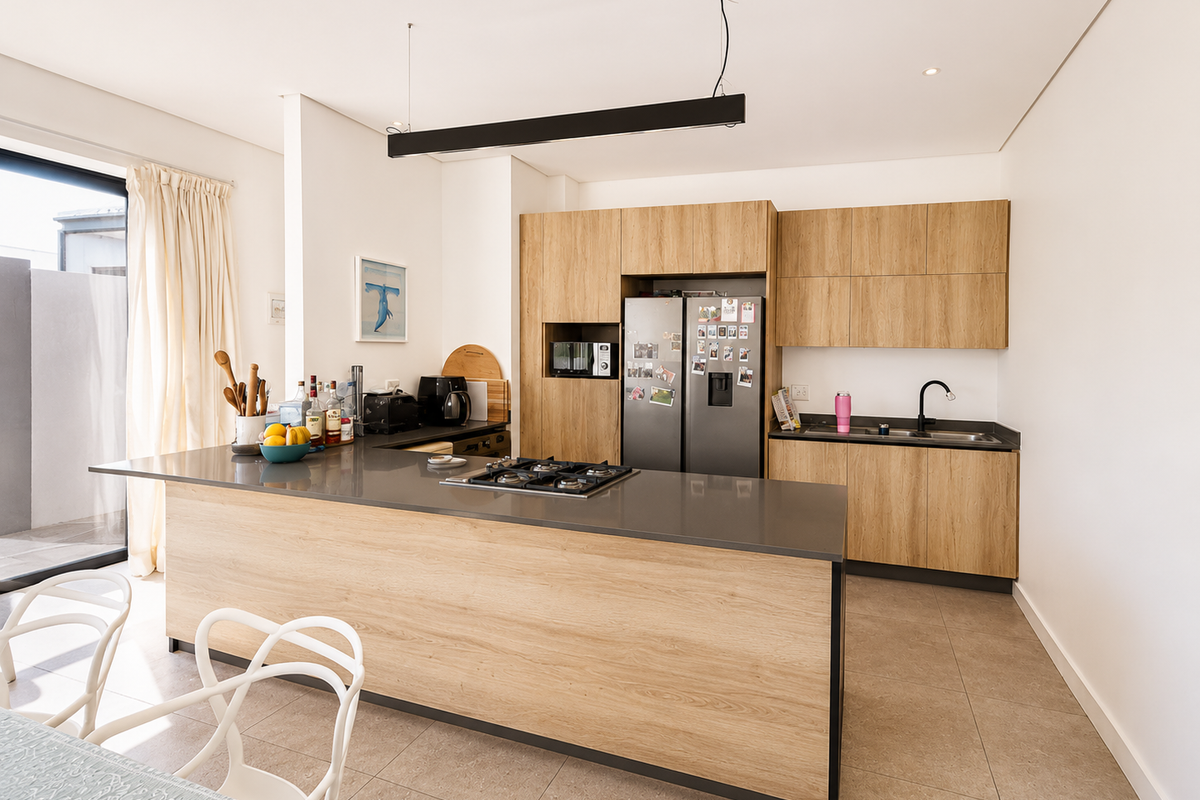 Modern kitchen featuring light wood cabinetry, stone countertops, a central island with a gas cooktop, and integrated appliances.