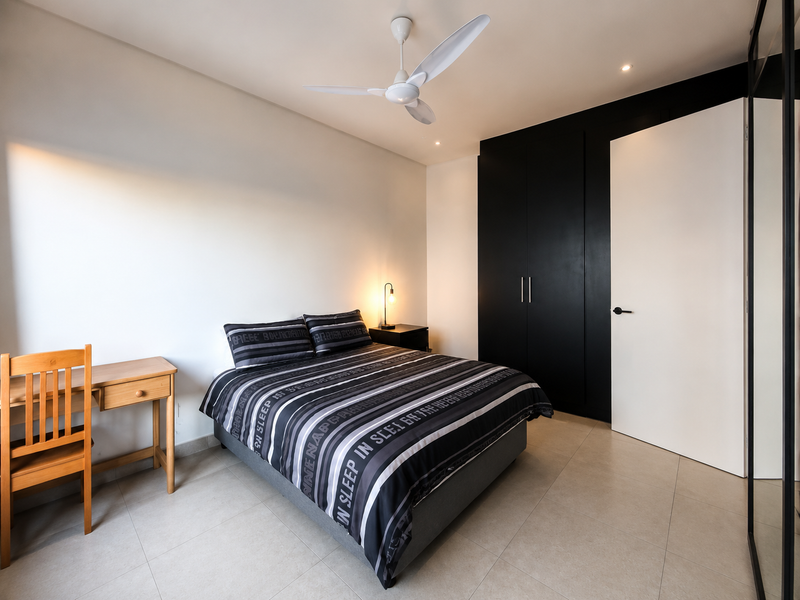 A modern bedroom featuring sleek black built-in cupboards, neutral tiled flooring, and a contemporary ceiling fan.