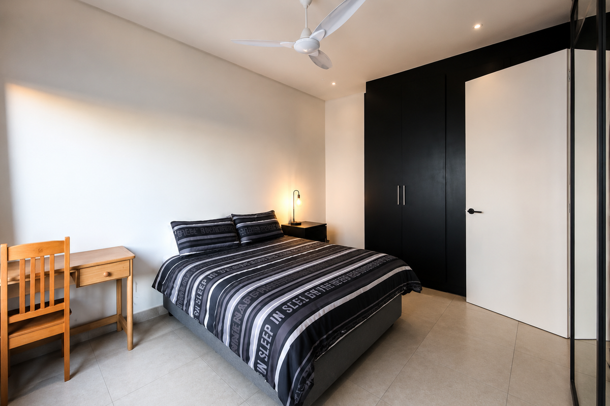 A modern bedroom featuring sleek black built-in cupboards, neutral tiled flooring, and a contemporary ceiling fan.
