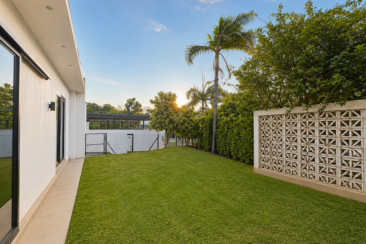 A well-maintained rear garden featuring a tiled patio, manicured lawn, and a decorative breeze block wall, providing a private and modern outdoor space.