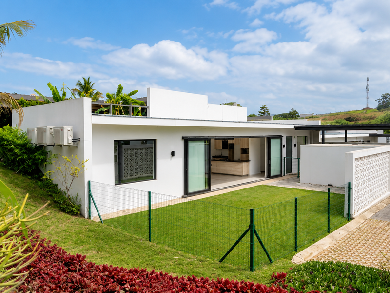 Modern townhouse exterior featuring a flat roof, sliding glass doors opening to a private fenced garden, and paved driveway access.