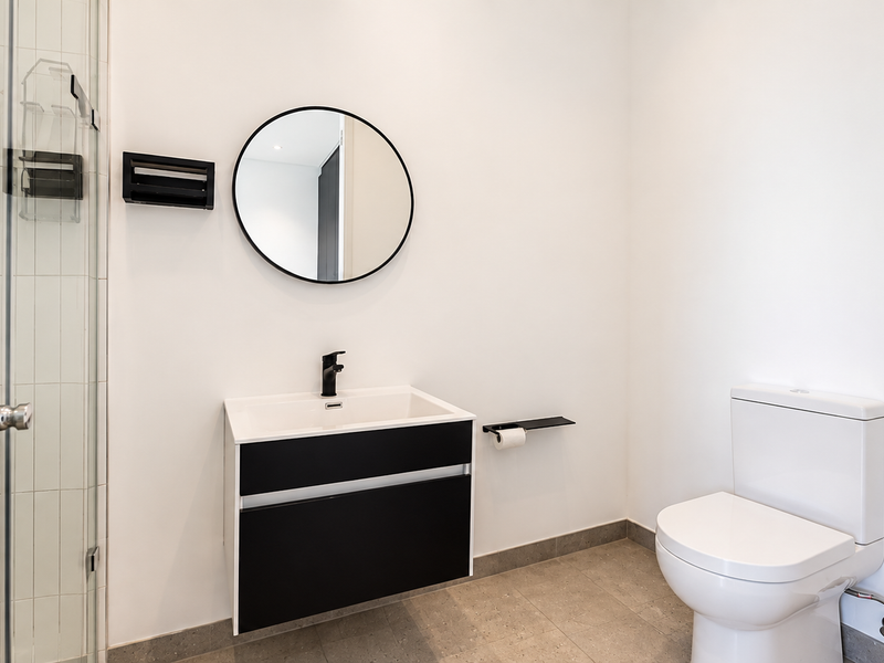 Modern bathroom featuring a wall-mounted vanity, basin, toilet, and a glass-enclosed shower with clean, contemporary finishes.