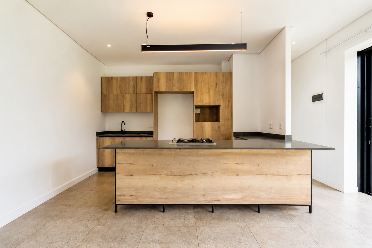 Modern open-plan kitchen featuring wood-finish cabinetry, a central island with a gas hob, and direct access to an outdoor patio area.