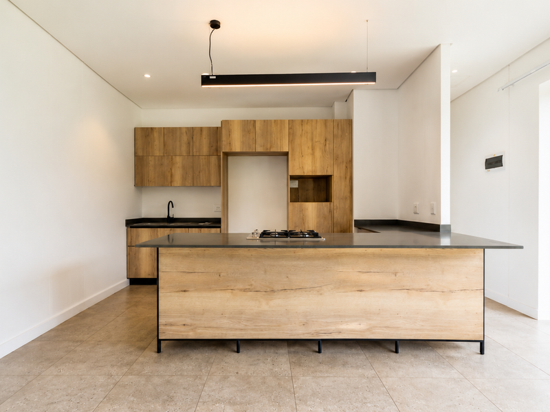 Modern open-plan kitchen featuring wood-finish cabinetry, a central island with a gas hob, and direct access to an outdoor patio area.