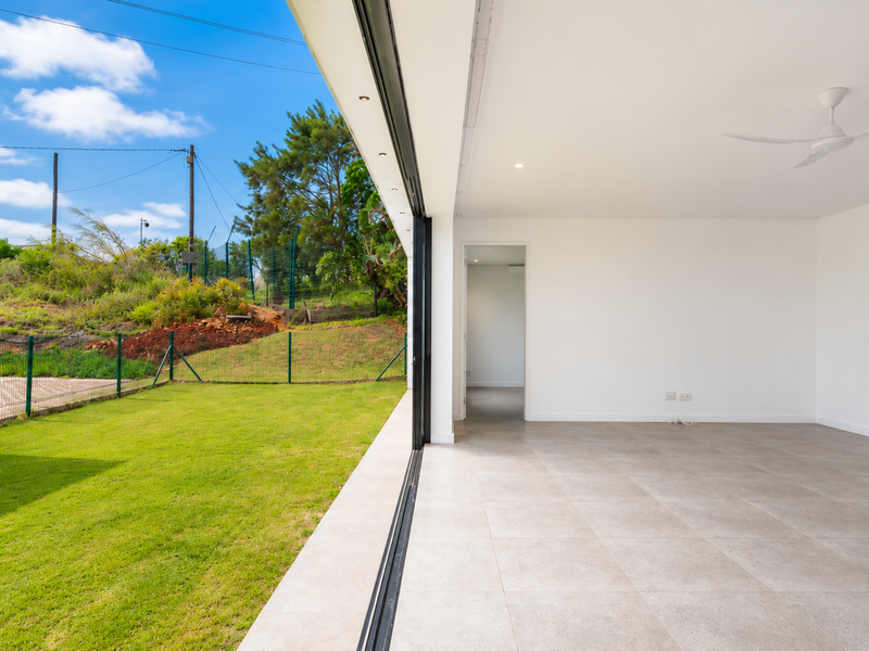 Bright open-plan living area featuring large sliding glass doors that open onto a private lawn, creating a seamless indoor-outdoor flow.