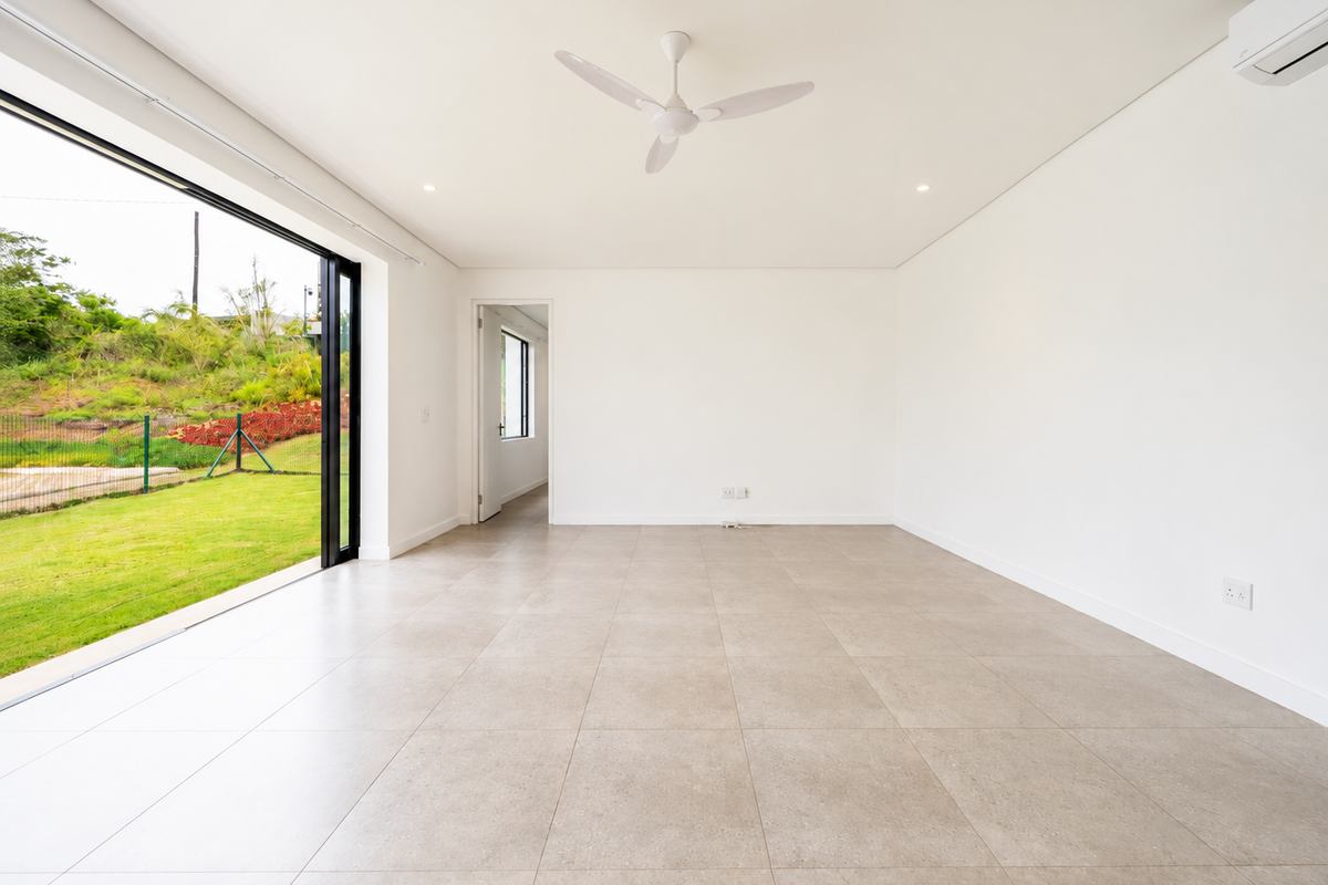 Bright and spacious open-plan living area featuring large sliding glass doors, neutral tiled flooring, a ceiling fan, and split-system air conditioning.