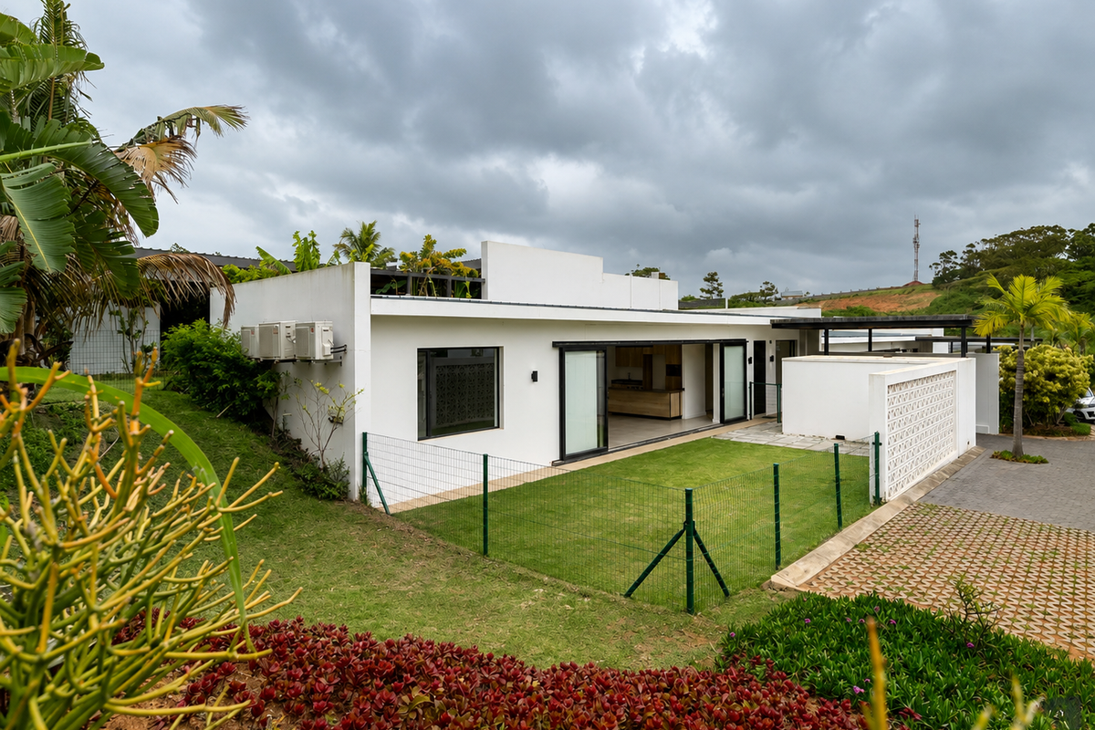 Rear view of a modern townhouse featuring a private garden, paved driveway, sliding glass doors, and a decorative breeze block wall.