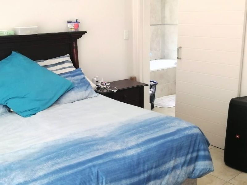A bedroom featuring tiled flooring and a sliding door providing access to an adjoining bathroom.